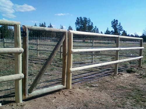 Custom pole fence with gate in pasture